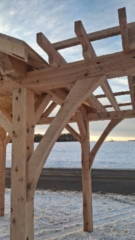 Wooden pergola frame on a snowy beach at sunset, with the ocean in the background