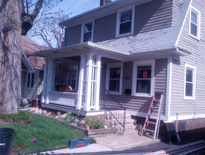 Two-story gray house with white trim and a front porch, viewed from the yard