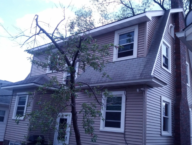 Two-story gray house with white trim and a bare tree in the front yard