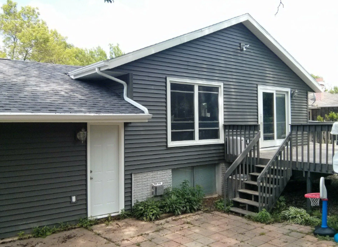 Gray house exterior with garage, white trim, front steps, and small brick patio.