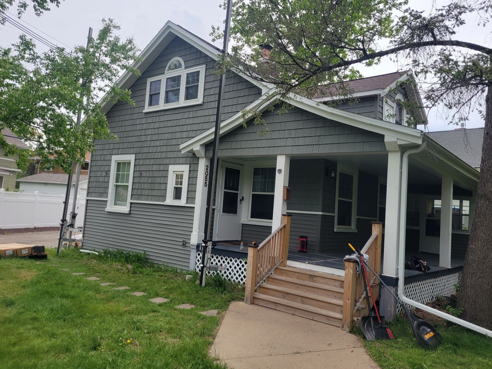 Gray house with front porch, steps, and white trim, viewed from the lawn
