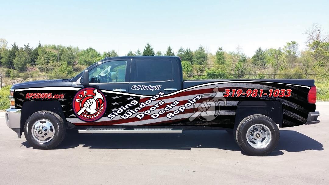 Customized black pickup truck with red and white graphics parked on a road