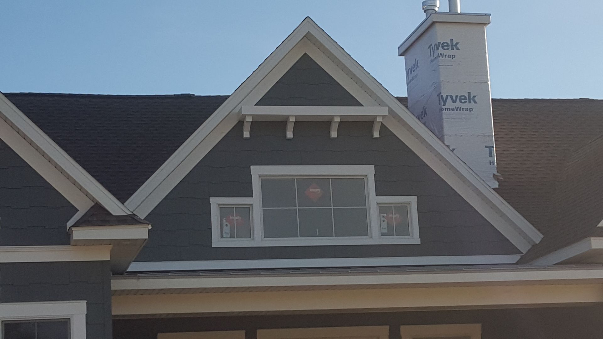 House roof with dormer windows and a white chimney against the sky