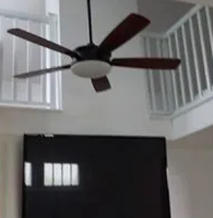 Ceiling fan above a dark doorway in a bright room with white railings
