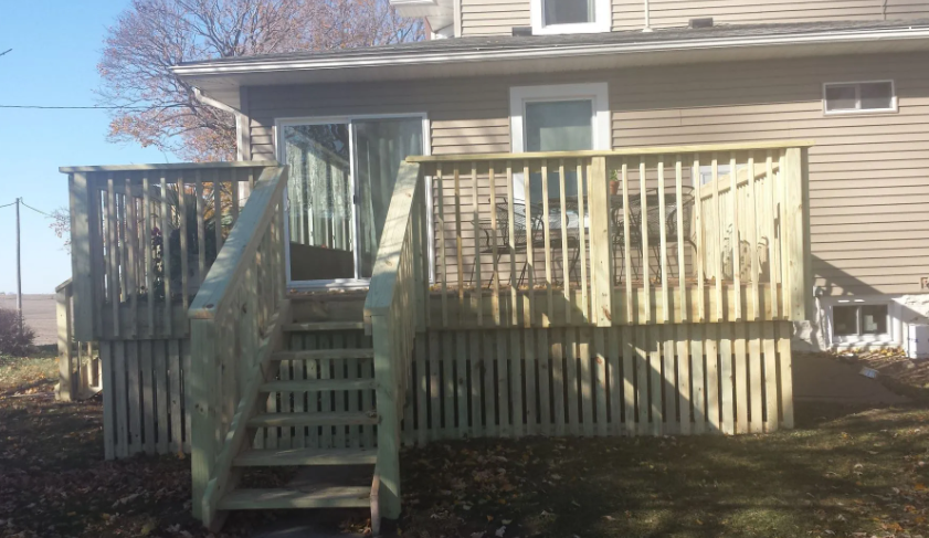 Front steps and wooden ramp leading to a beige house with a fenced porch.