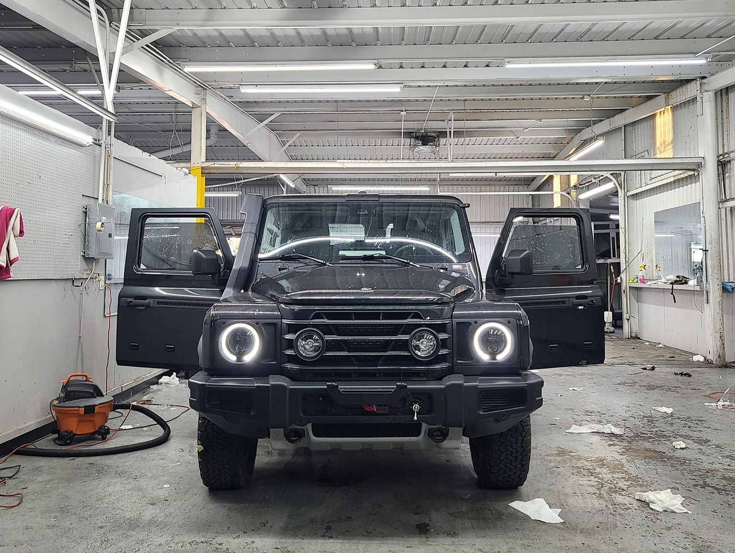 A black suv is parked in a garage with its doors open.