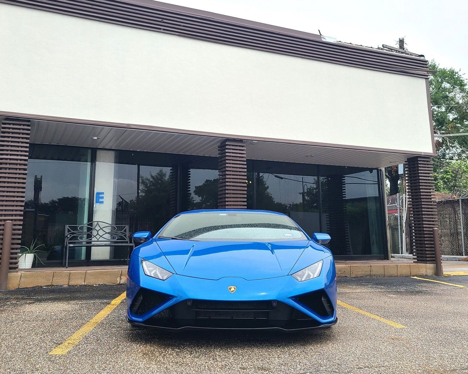A blue sports car is parked in front of a building