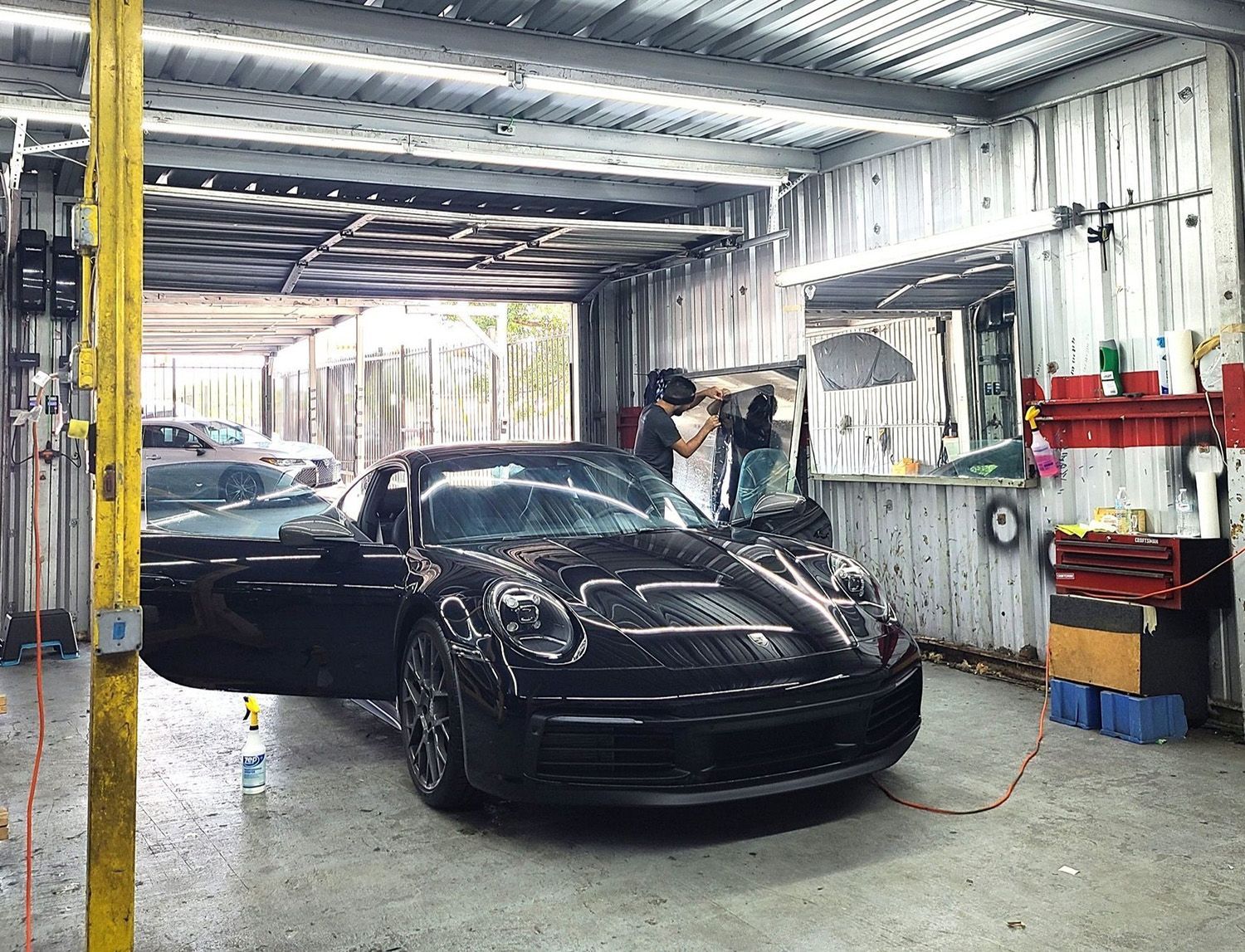 A man is working on a black sports car in a garage.