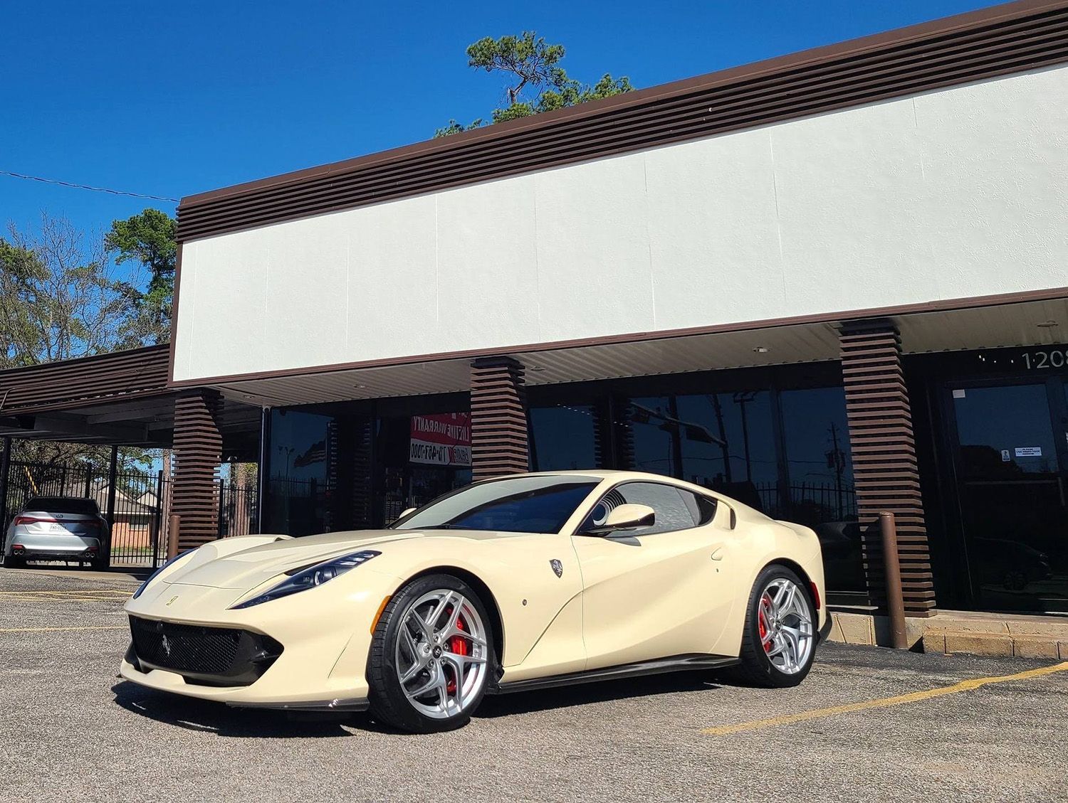 A white ferrari is parked in front of a building.