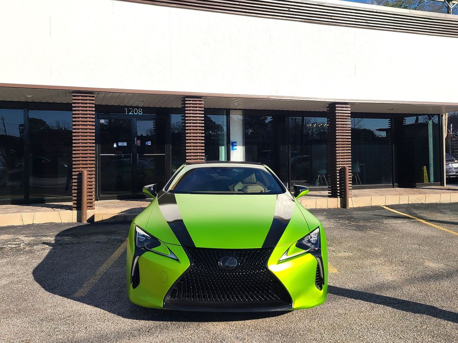 A green sports car is parked in front of a building.