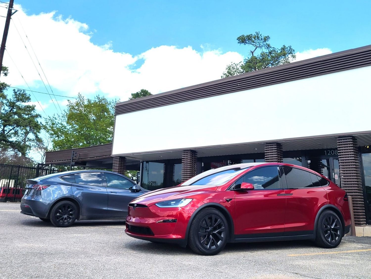 Two tesla cars are parked in front of a building.
