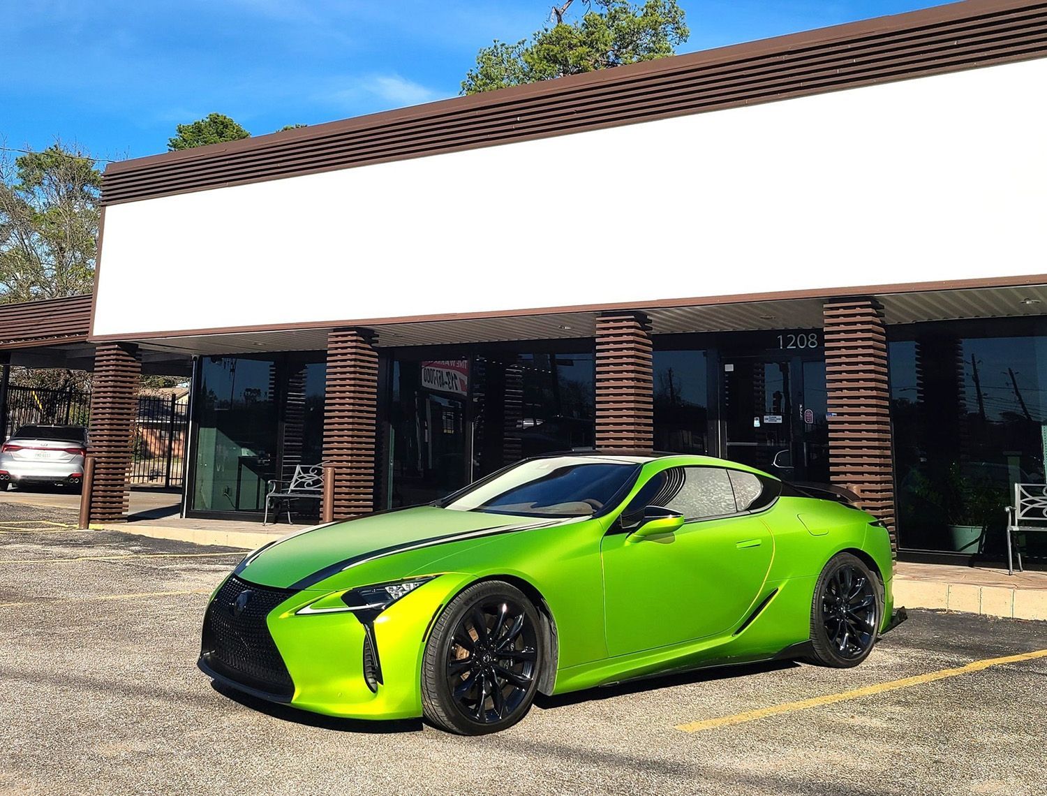 A green sports car is parked in front of a building.