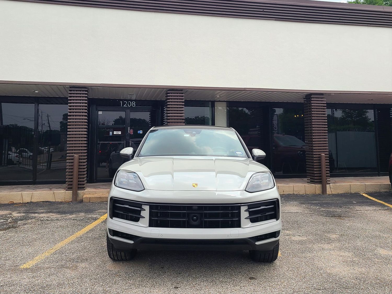 A white porsche macan is parked in front of a building.