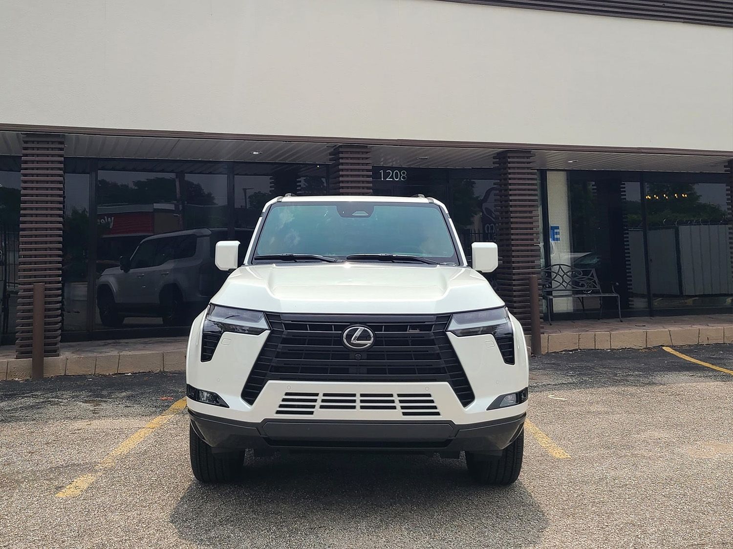 A white lexus is parked in a parking lot in front of a building.