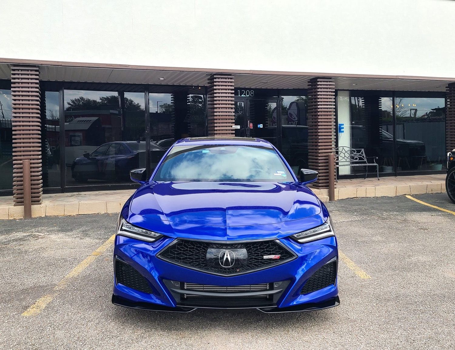 A blue car is parked in a parking lot in front of a building.