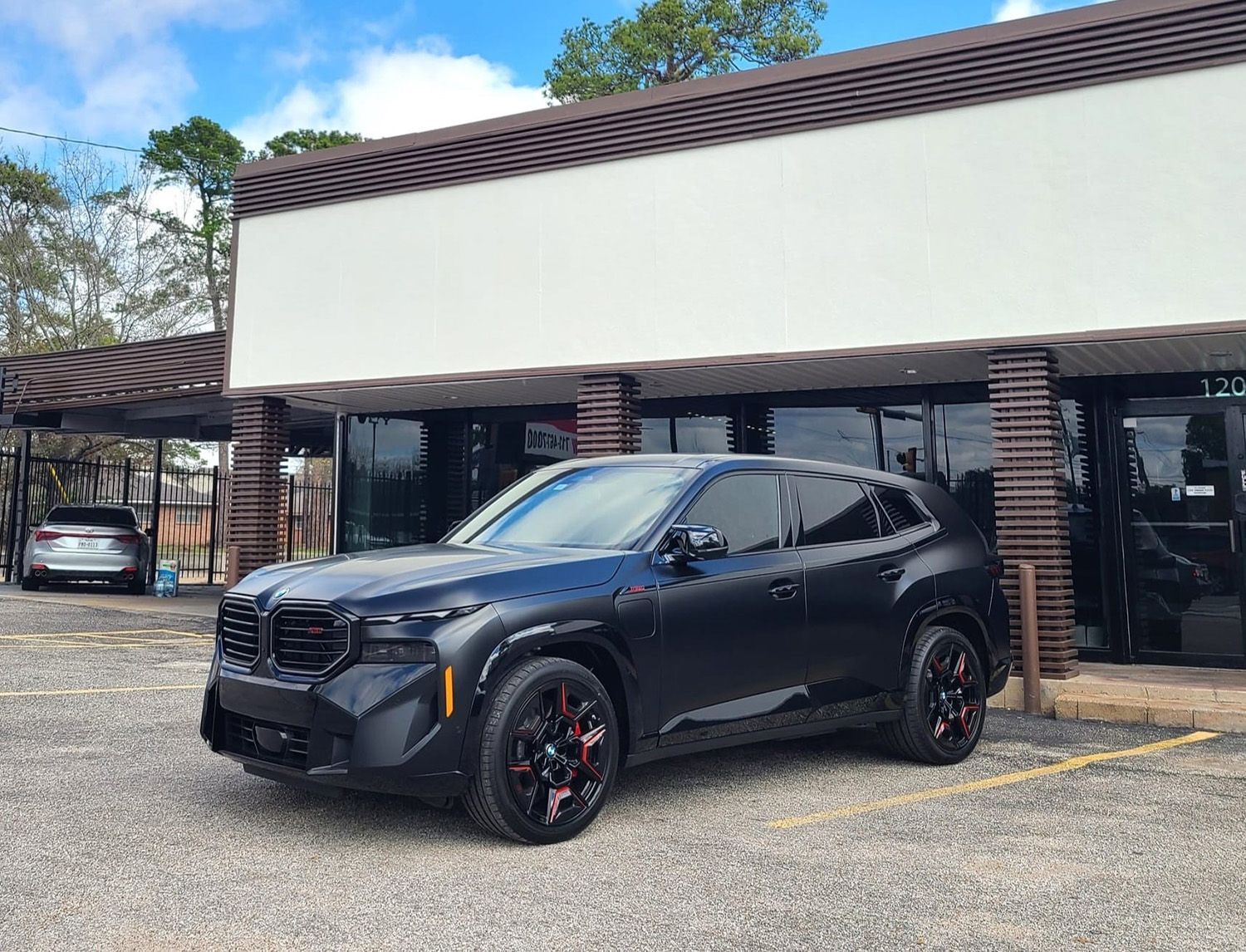 A black car is parked in front of a building.