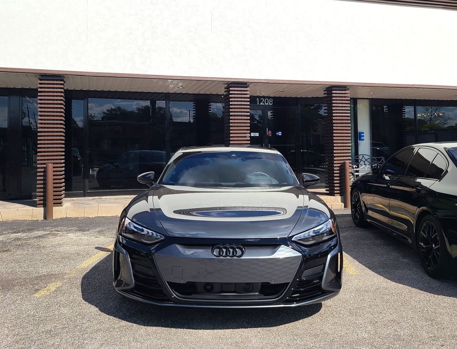 A black audi e-tron is parked in front of a building.