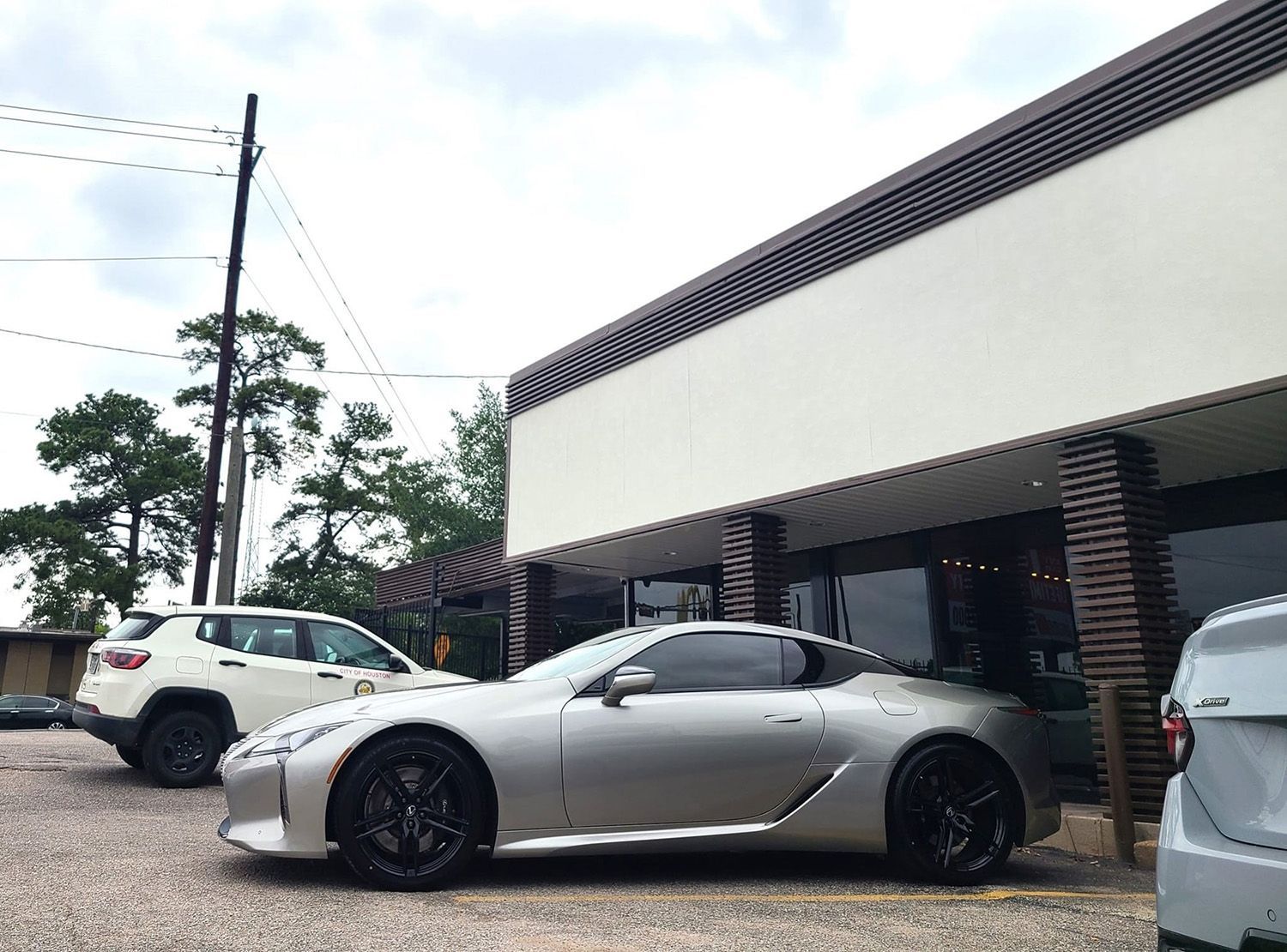 A silver sports car is parked in front of a building.