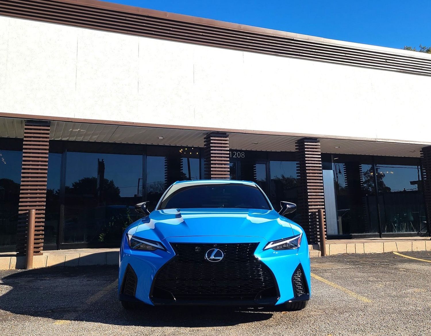 A blue Lexus is parked in front of a building
