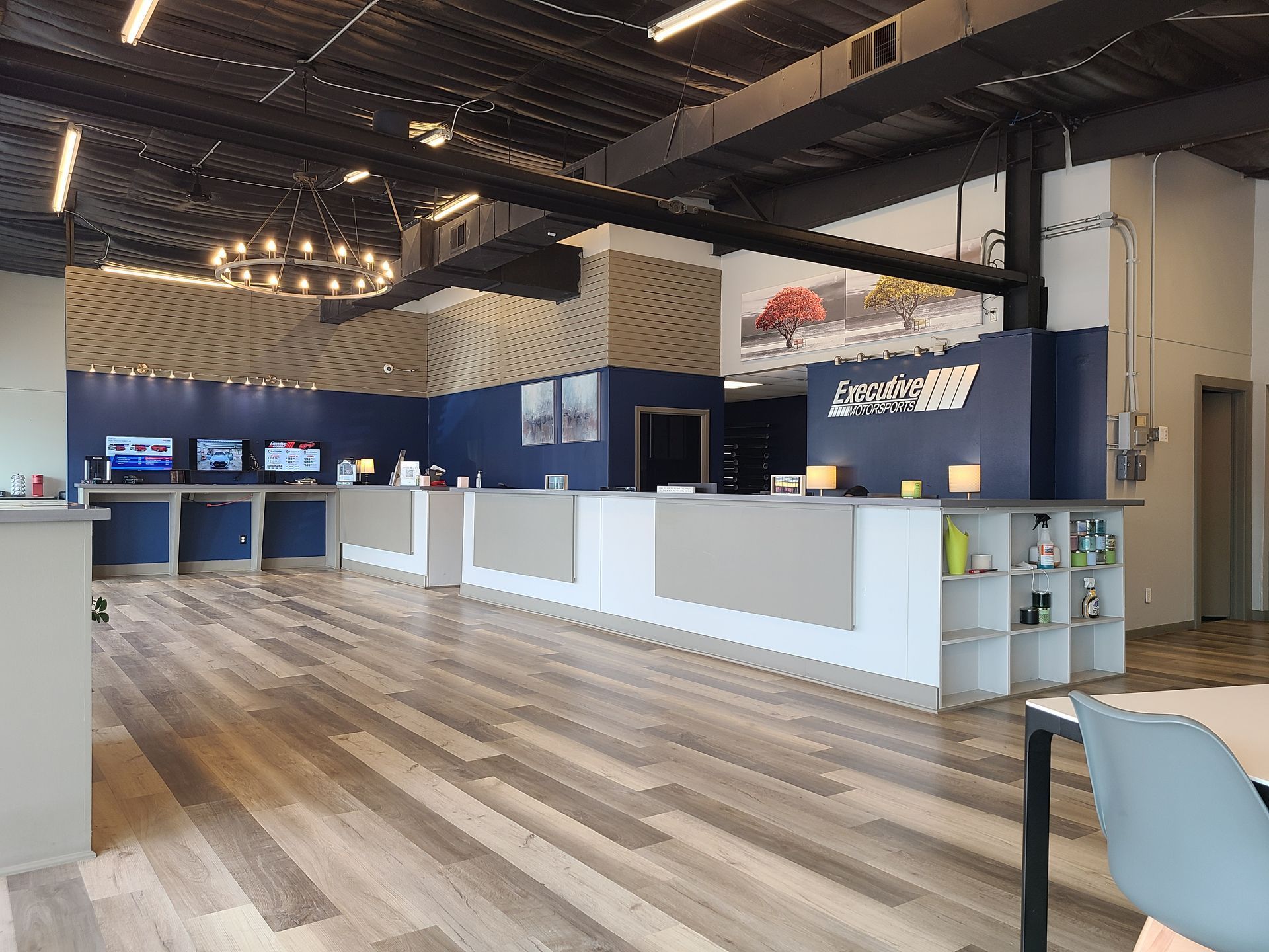 Modern lobby with wood floors, white counters, blue booths, and pendant lights in a spacious interior