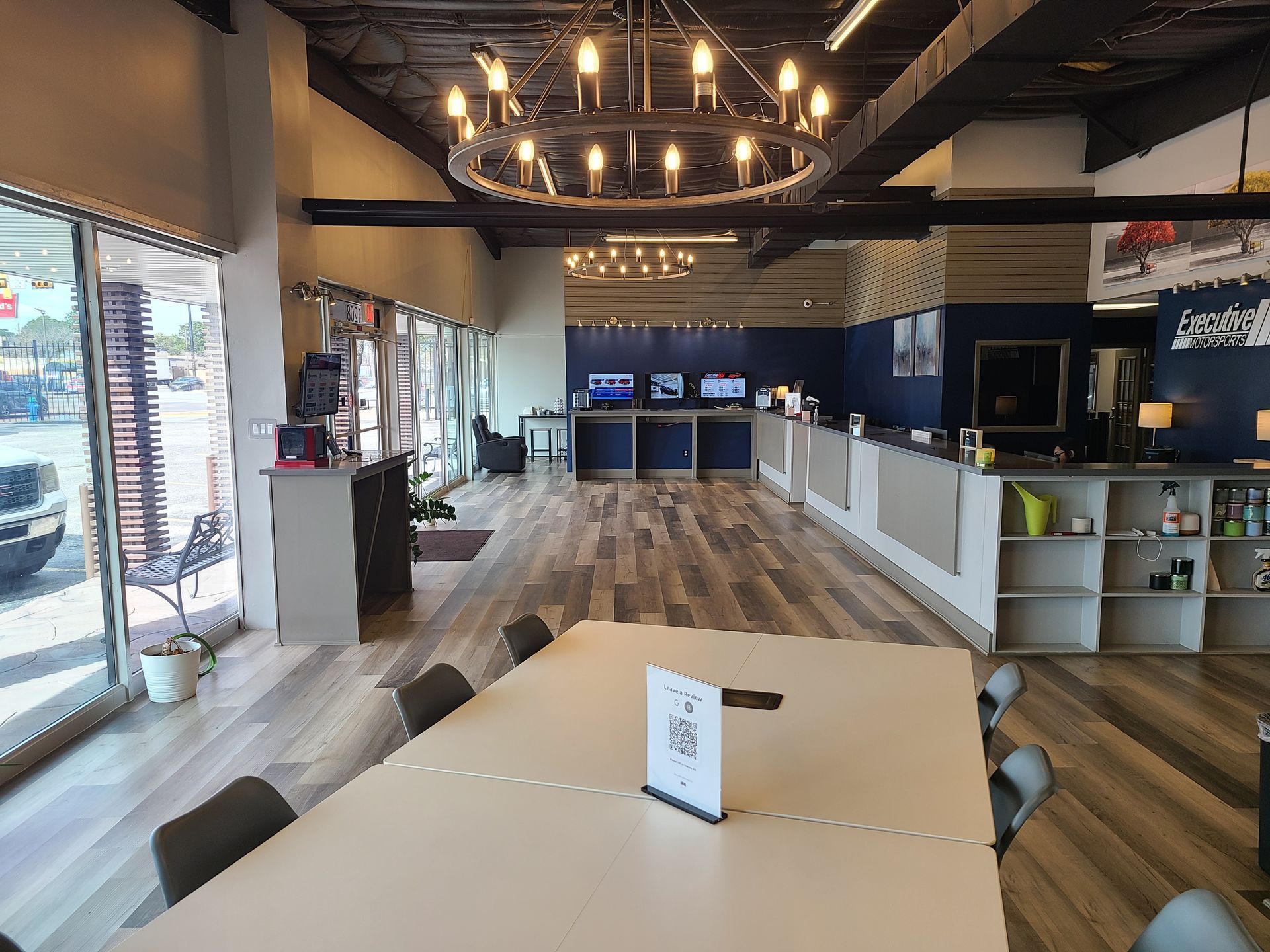 Empty café interior with wood floors, long tables, and warm pendant lights
