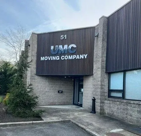 Front of TMC Moving Company building with gray siding, number 51, and a small entrance walkway