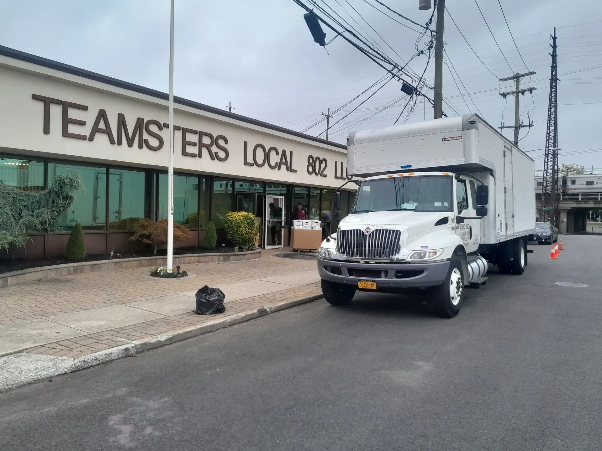 White box truck parked outside a Teamsters Local 802 building on a city street