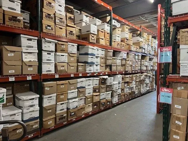 Warehouse aisle with tall red shelving stacked with labeled cardboard boxes