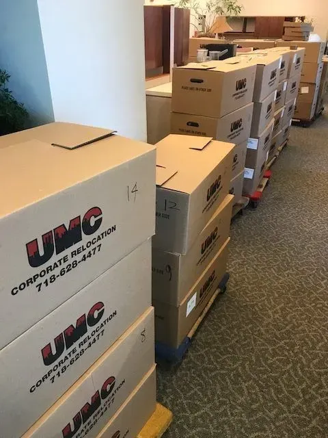 Boxes of UMC computer parts stacked in a warehouse aisle on pallets