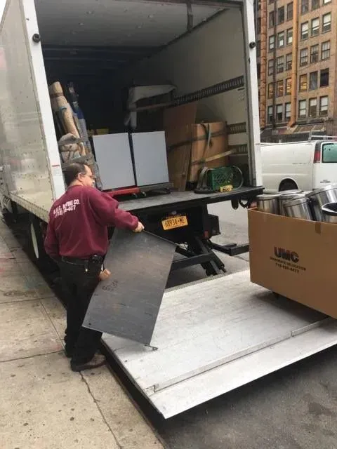 Person unloading a truck with a ramp and boxes on a city street
