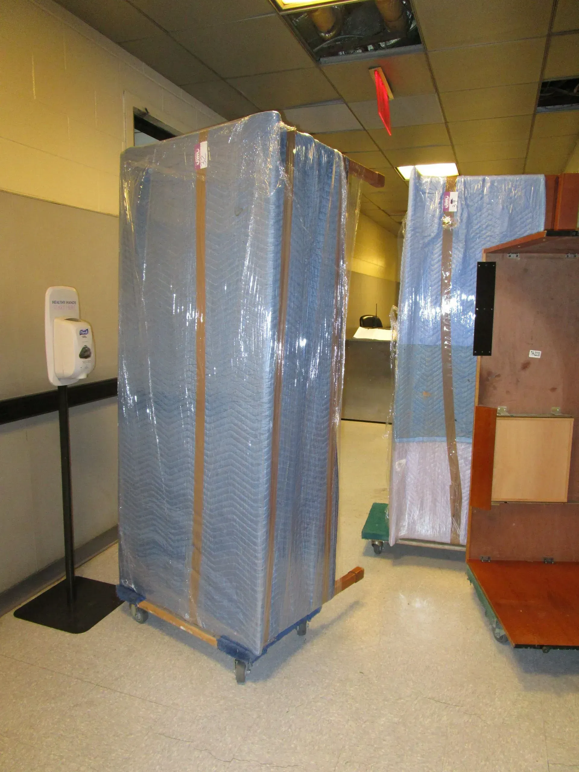 Blue wrapped pallets and a red cart in a warehouse hallway