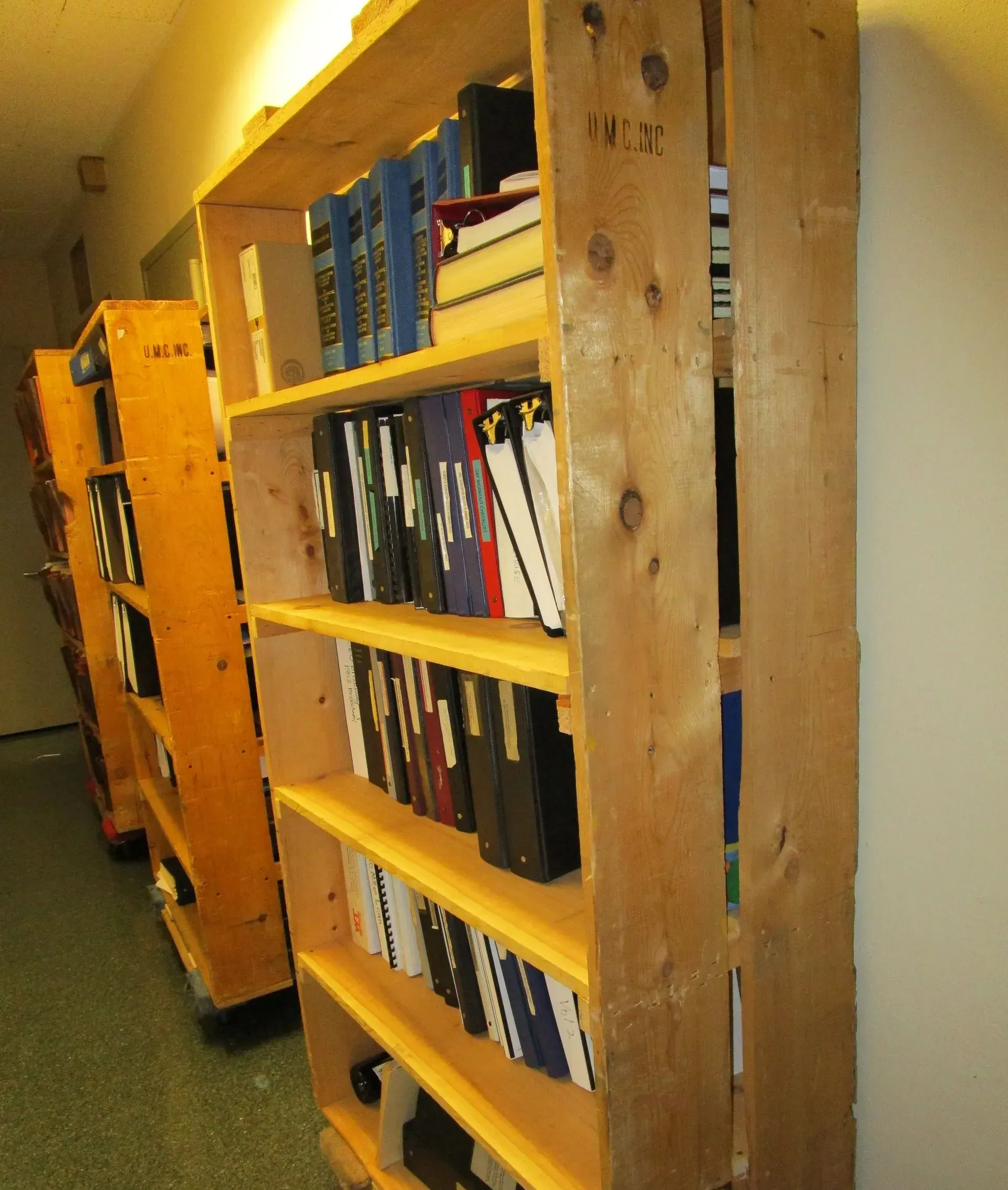 Narrow hallway with wooden bookshelves filled with books along the wall.