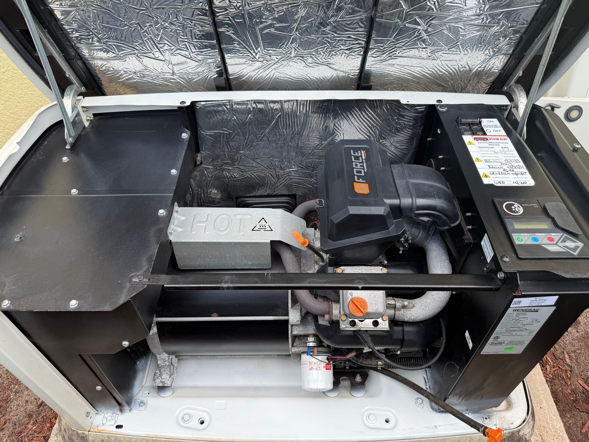 Open generator with black engine and components inside white casing.