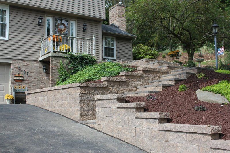 A house with a stone wall and stairs leading up to it.