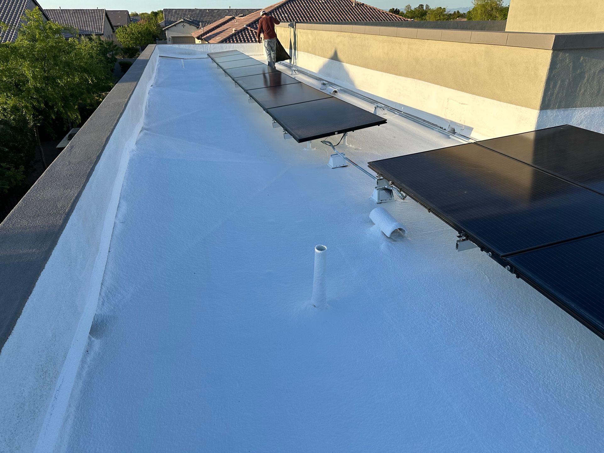 A white roof with black solar panels on it.