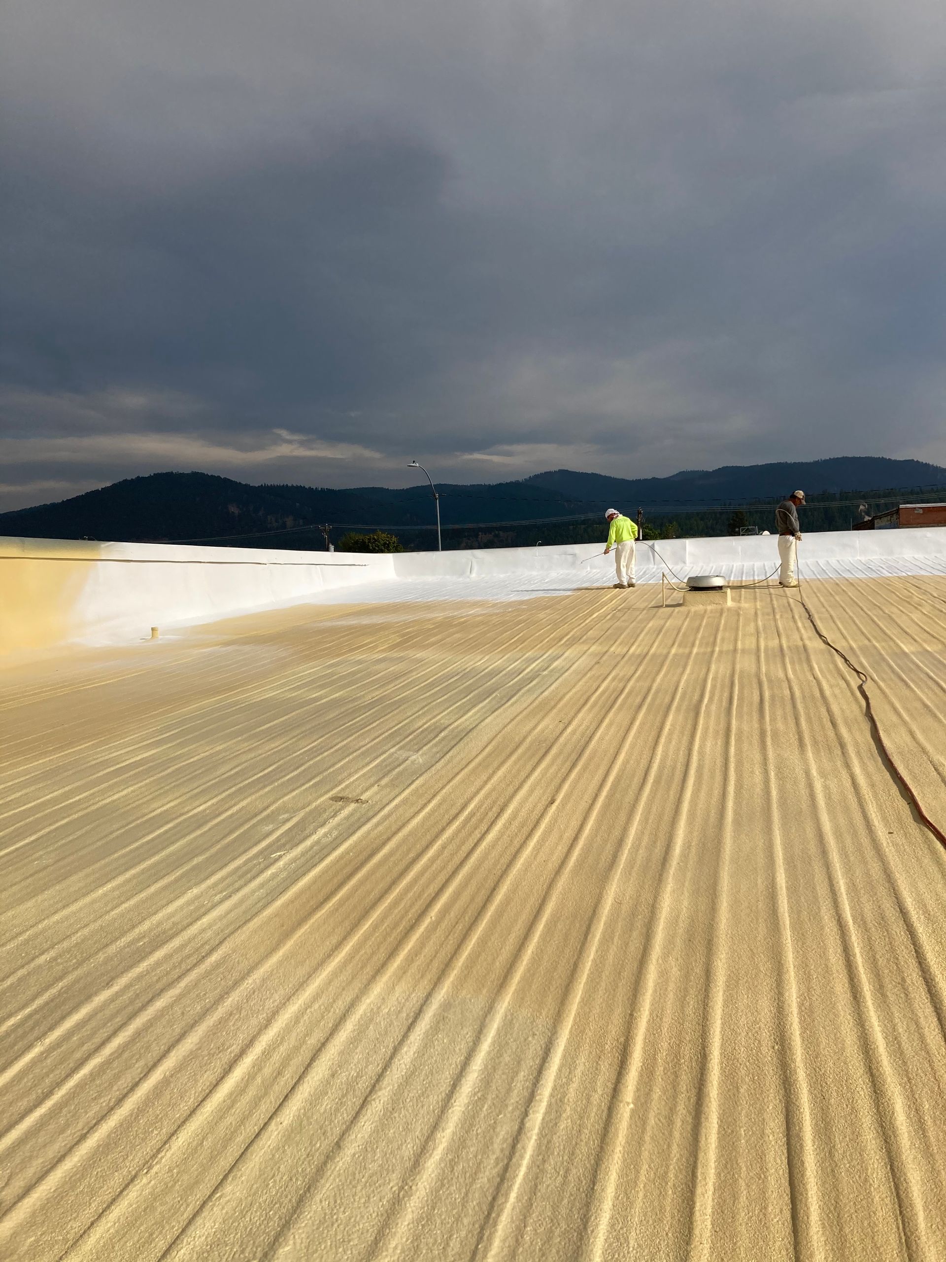 A man is standing on a sandy beach with mountains in the background.