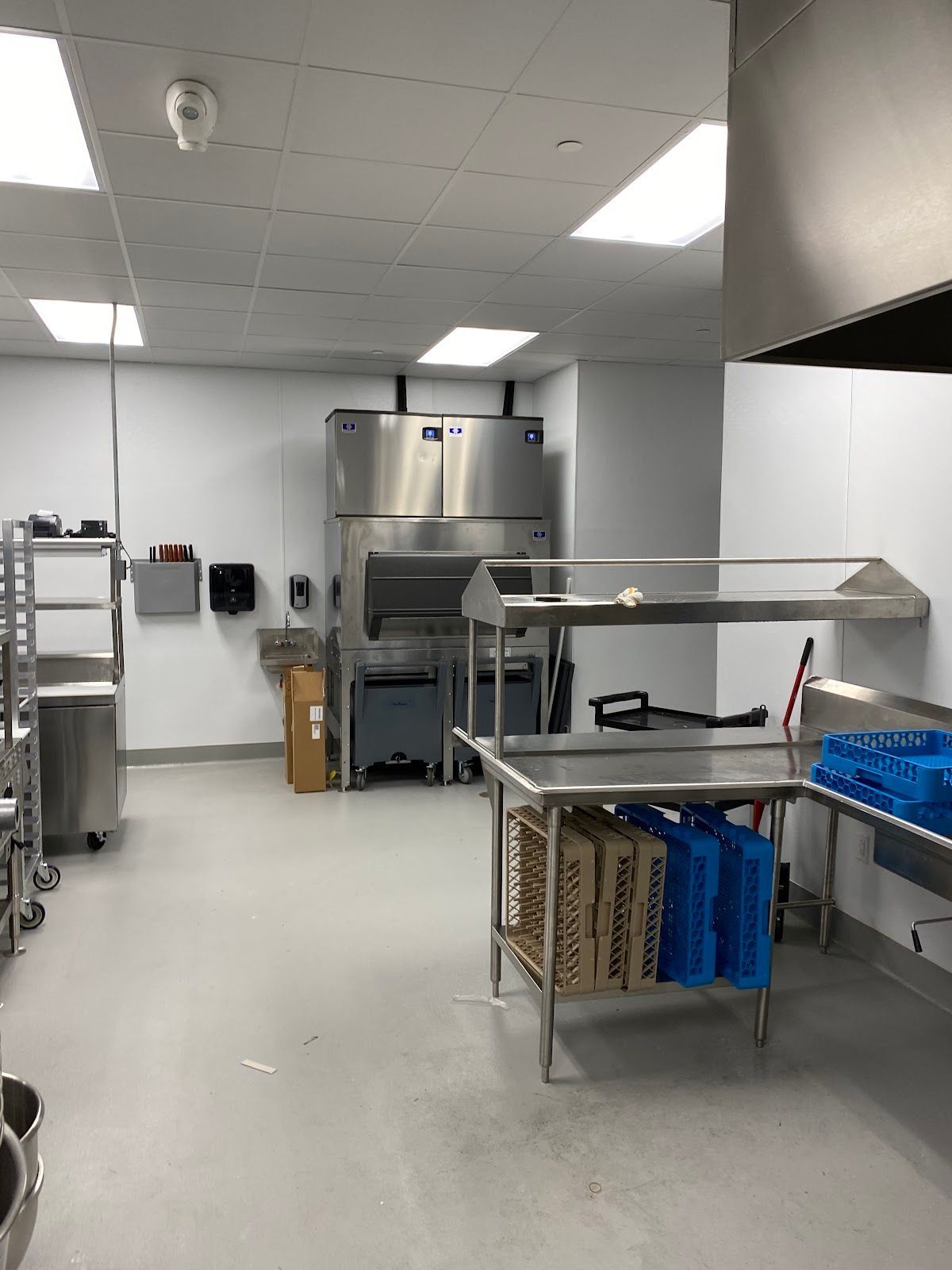 Commercial kitchen with stainless steel tables and equipment under bright ceiling lights