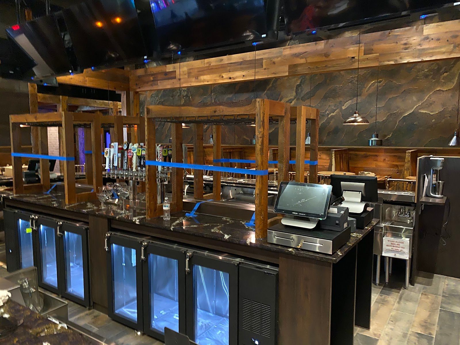 Empty upscale bar with illuminated blue counters, wooden shelves, and a cash register area
