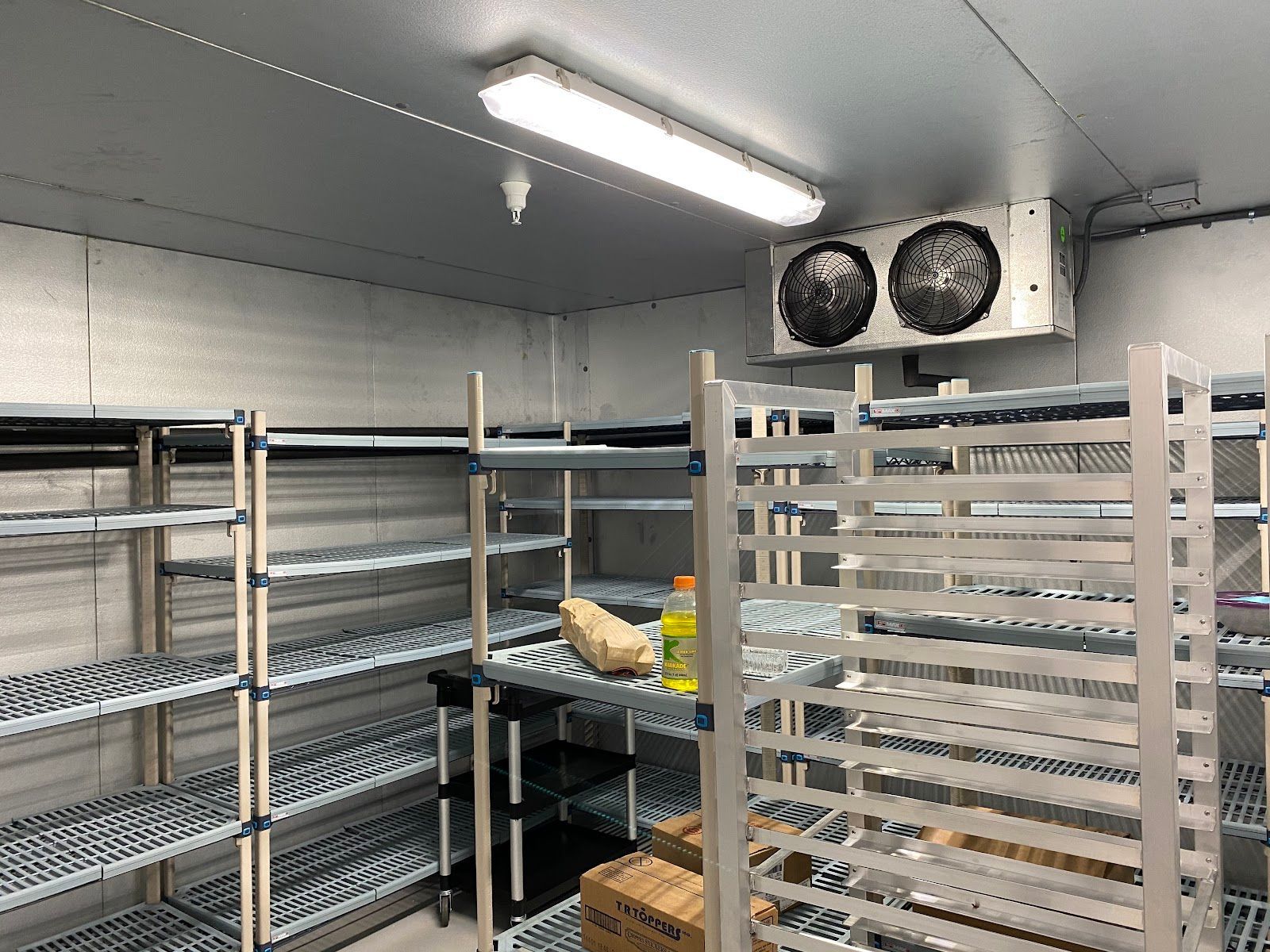 Empty walk-in cooler with metal shelving and a fluorescent light overhead