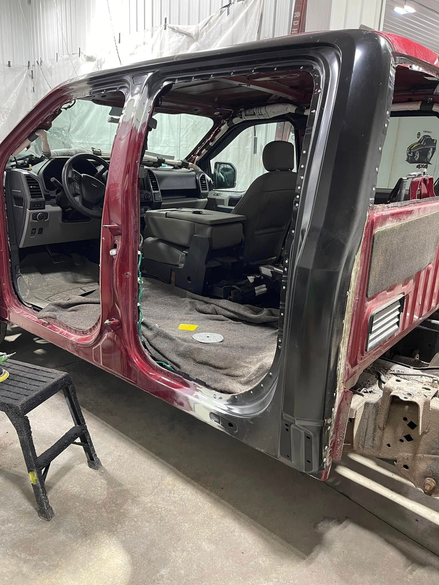 Red SUV with side body panel removed, exposing the interior during vehicle repair in a garage.