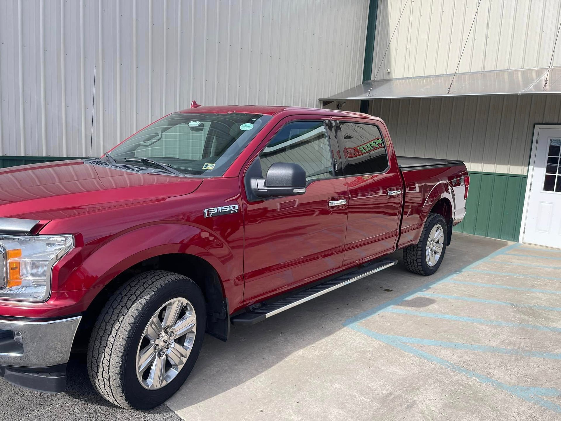 Maroon pickup truck parked beside a building under bright daylight