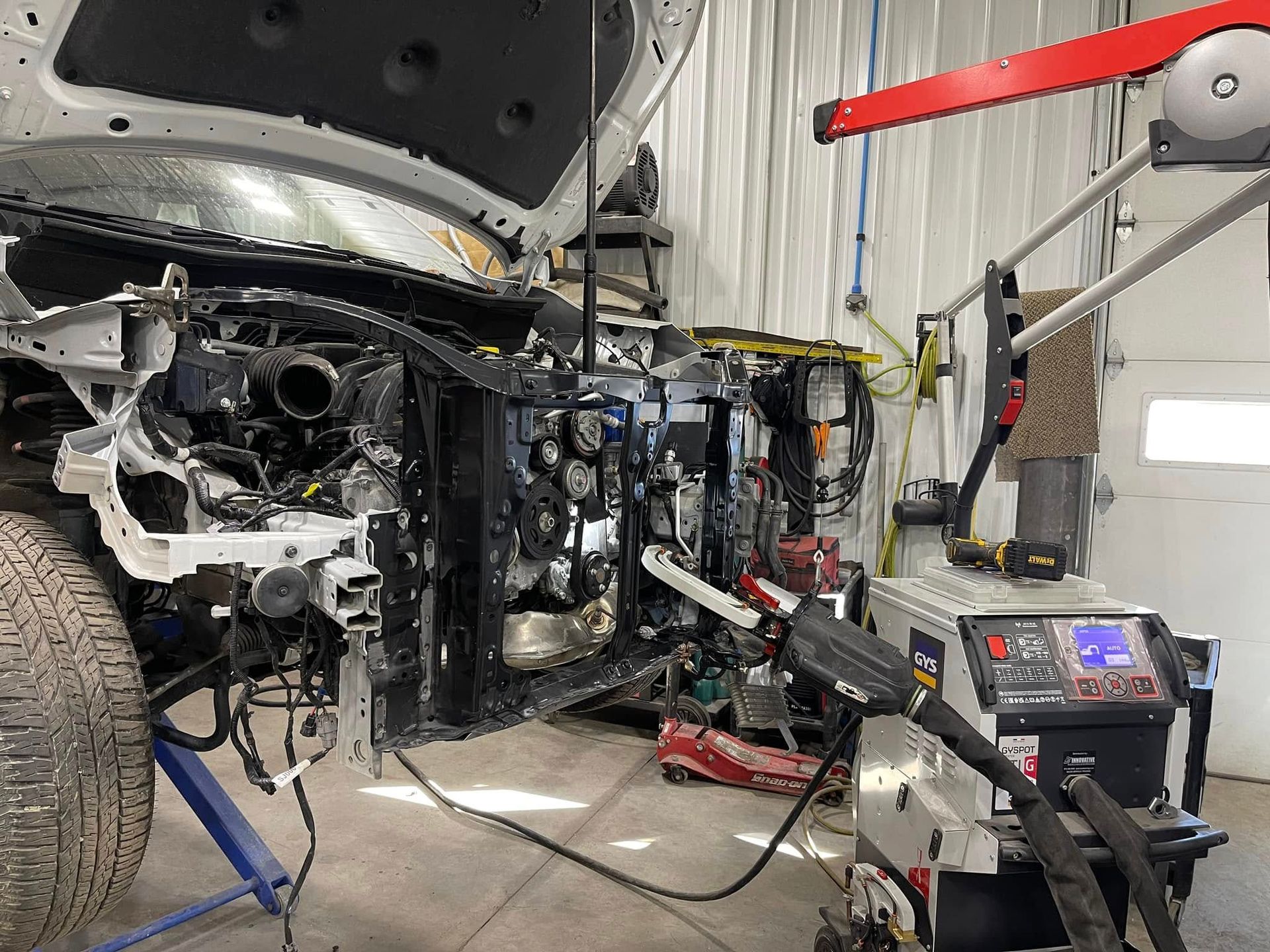 Auto body repair shop with a partially disassembled car and repair equipment nearby