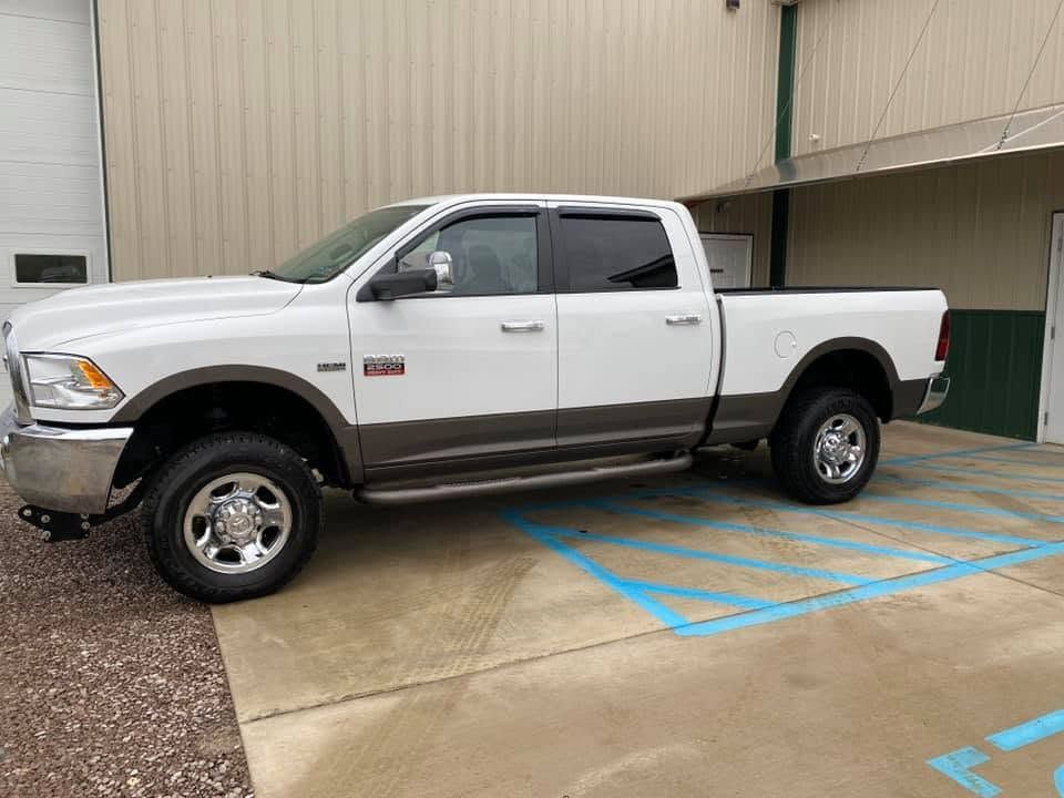 White pickup truck parked in a blue-striped accessible parking space beside a beige building.