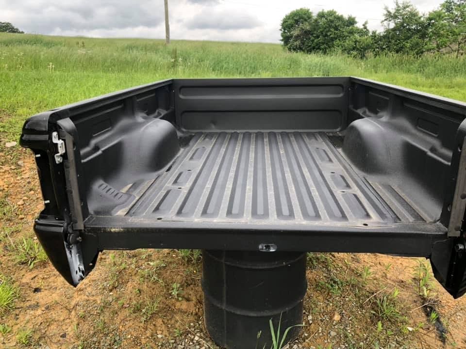 Empty black pickup truck bed outdoors on a cloudy day