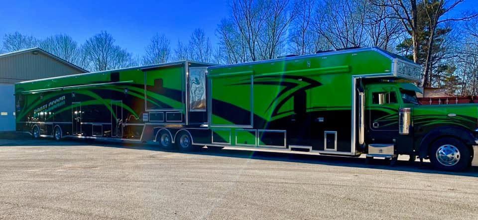Green semi-truck with matching trailer parked outdoors on a sunny day