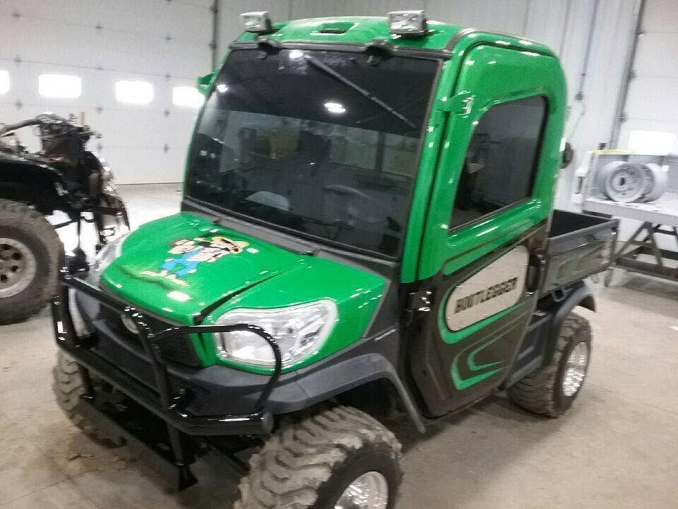 Green utility vehicle with large tires parked indoors in a garage-like setting
