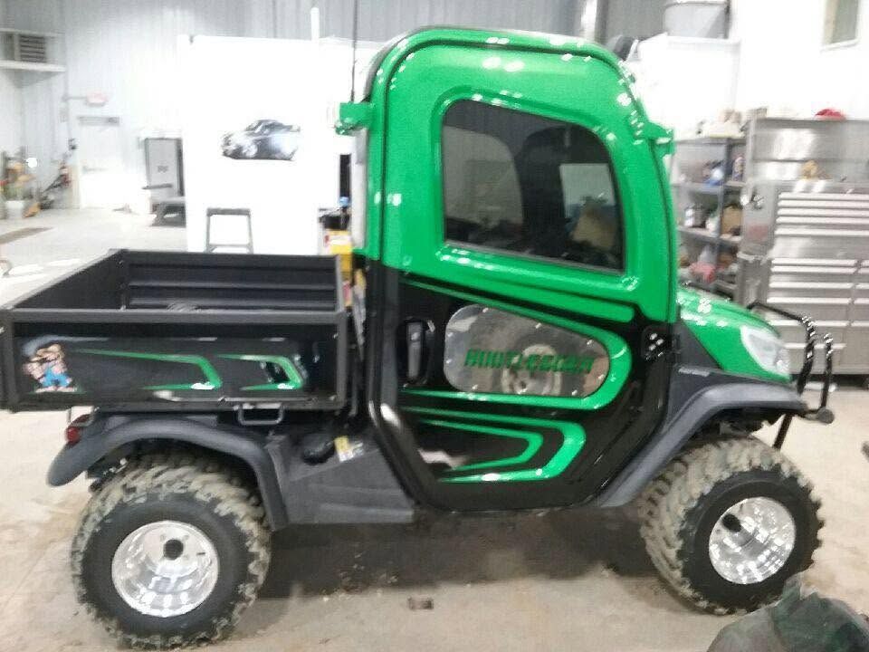 Green side-by-side utility vehicle with black accents in an indoor showroom