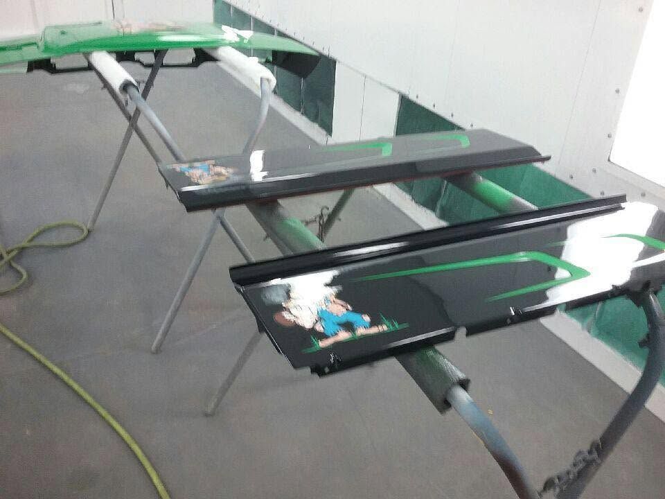 Damaged black and green machine parts with broken glass scattered on a gray floor