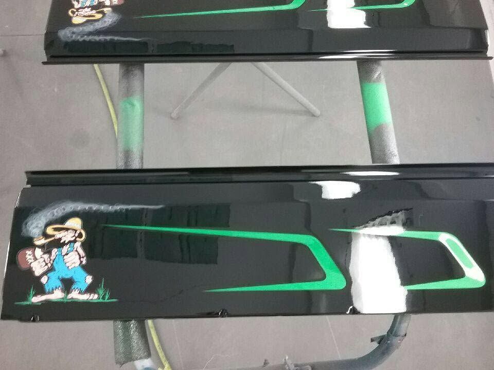 Black glossy bench or table with green trim and a small cartoon sticker on a gray floor