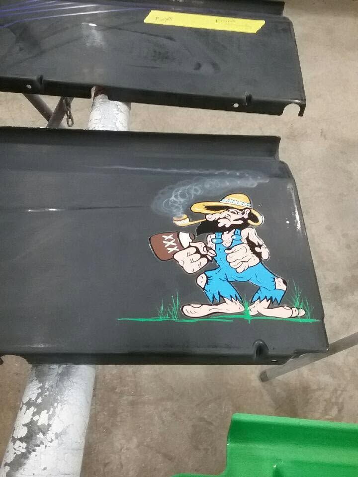 Cartoon character decal on a black surface, with another black bench and a green bin in the background.